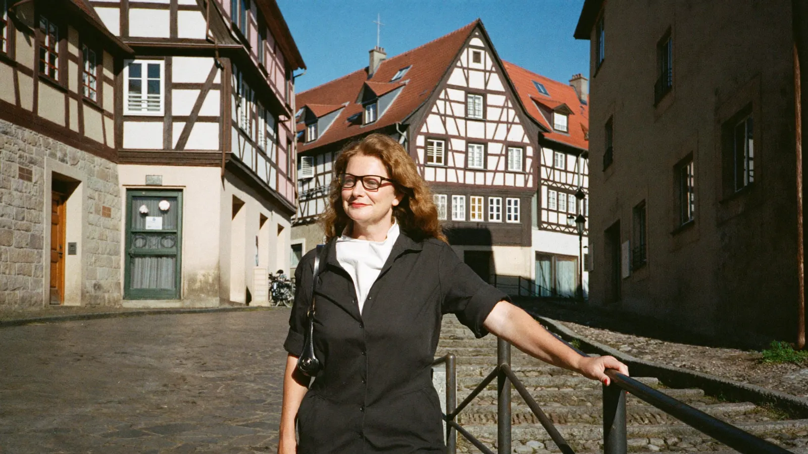 Frau mit Brille auf einer Altstadttreppe.